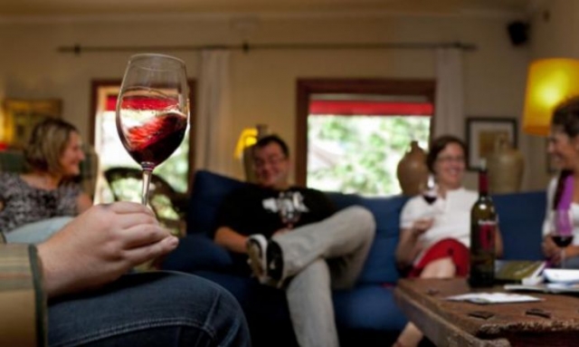grupo de amigos sentados en el sofa tomando una copa de vino